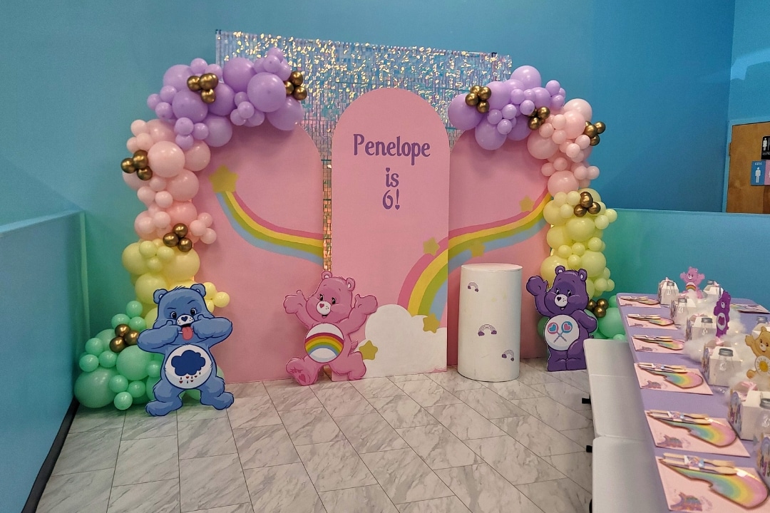 Care Bears themed 6th birthday party with rainbow backdrop and pastel balloons at Kidz Kastle RI