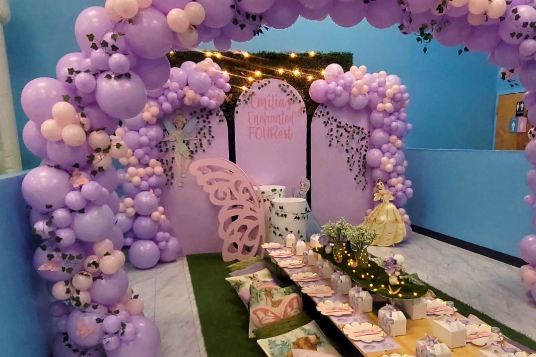 Enchanted Forest themed kids birthday party with purple balloon arch and fairy backdrop at Kidz Kastle RI