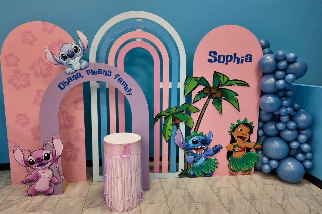 Lilo and Stitch themed birthday party with Ohana means family backdrop and tropical balloon decor at Kidz Kastle RI