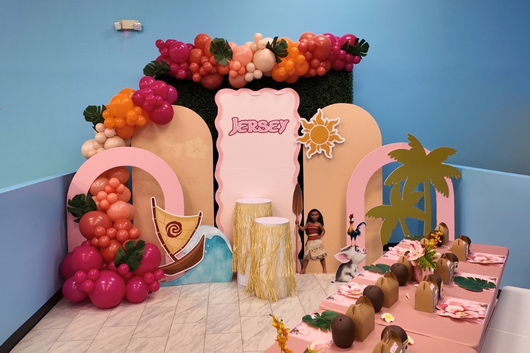 Moana themed girls birthday party with tropical balloon garland, palm tree cutouts, and custom arch backdrop at Kidz Kastle in Rhode Island.
