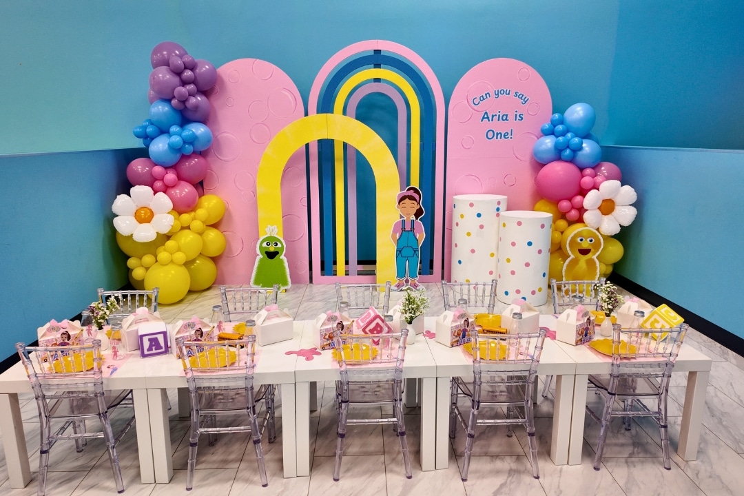 Ms. Rachel themed first birthday party with pink and purple balloon arches and custom table settings at Kidz Kastle RI