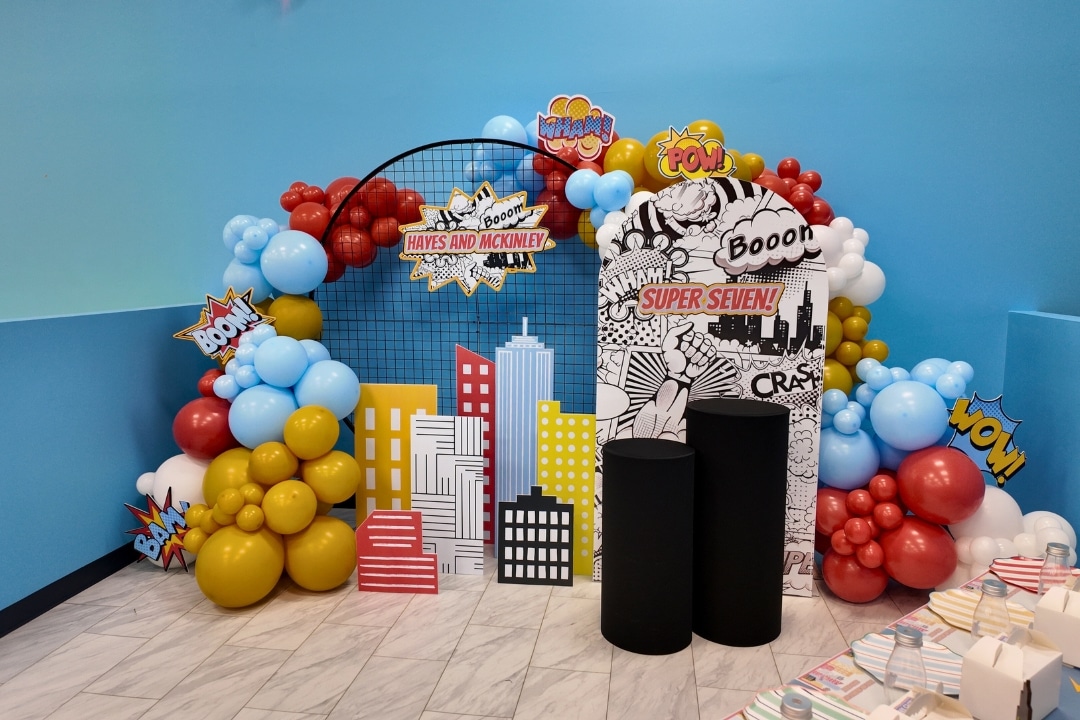 Custom superhero cityscape birthday party theme with comic book backdrops and professional balloon styling at Kidz Kastle RI