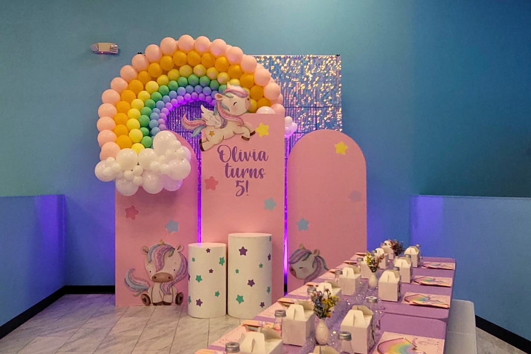 Magical unicorn and rainbow themed birthday party with shimmer wall and pastel balloon arch at Kidz Kastle RI