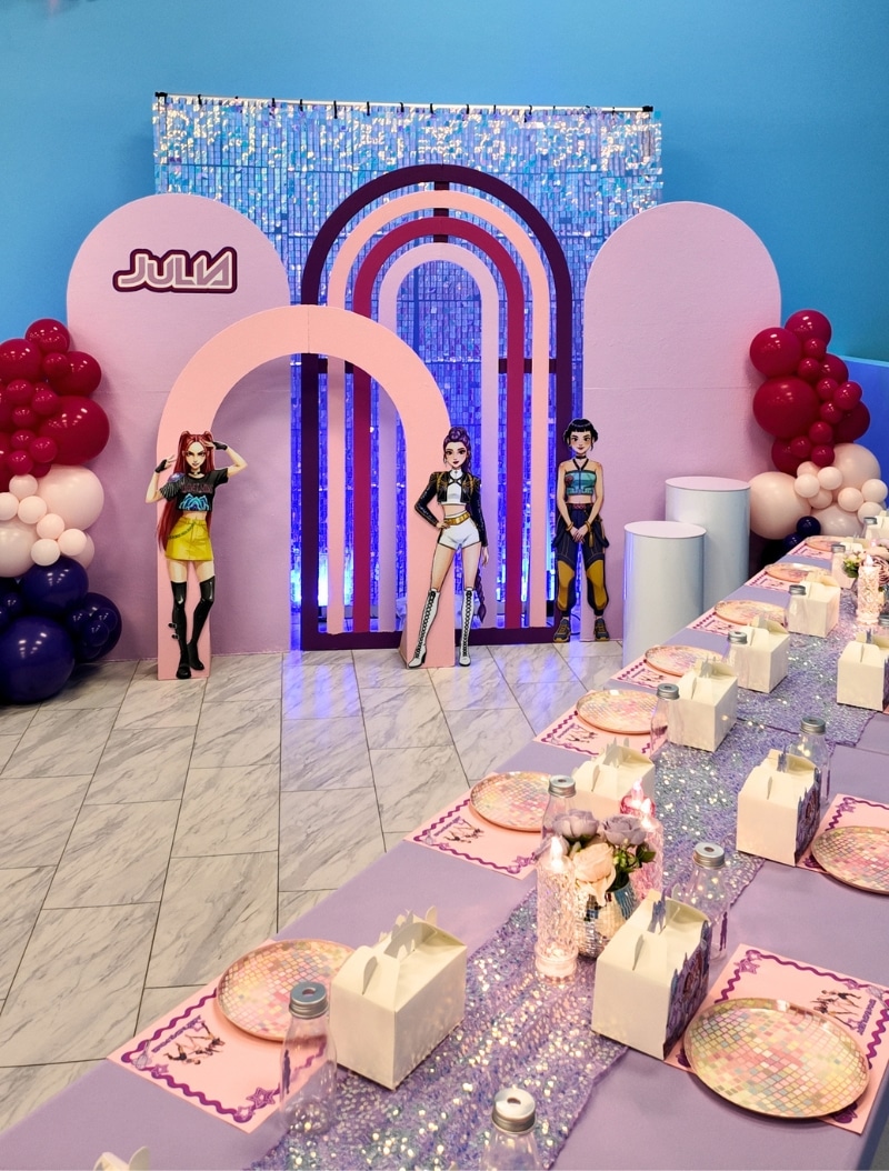 Private K-Pop themed girl's birthday party room at Kidz Kastle with purple shimmer backdrop, custom character standees, and disco-themed table decor.