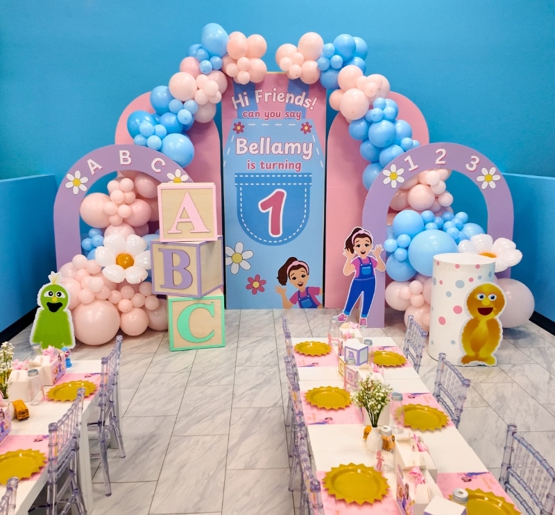 Colorful first-birthday setup with custom backdrop, balloon arch, and themed table settings for a private kids' birthday party in Warwick, RI, at Kidz Kastle.