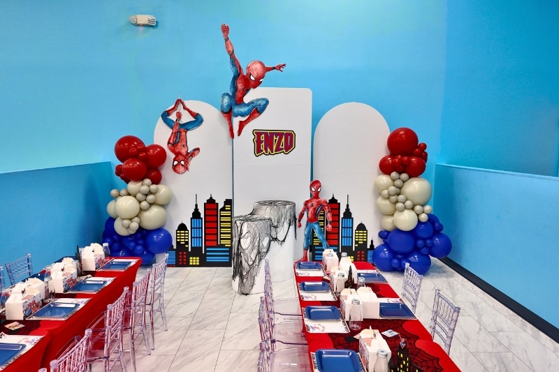 Custom Spider-Man themed birthday party setup at Kidz Kastle in Warwick, RI, featuring professional backdrops, superhero cutouts, balloon columns, and themed table settings.